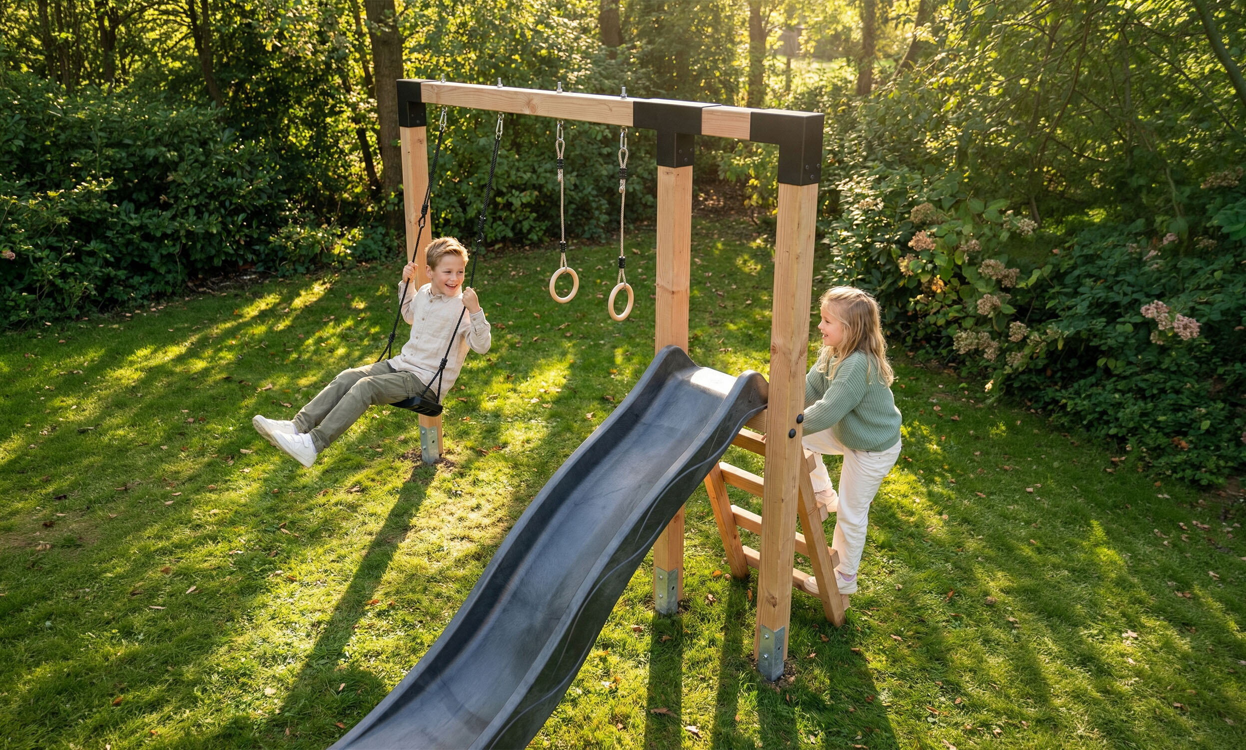 Deux enfants jouent dans le jardin sur une structure de jeu en bois avec une balan&ccedil;oire, des anneaux et un toboggan noir.
